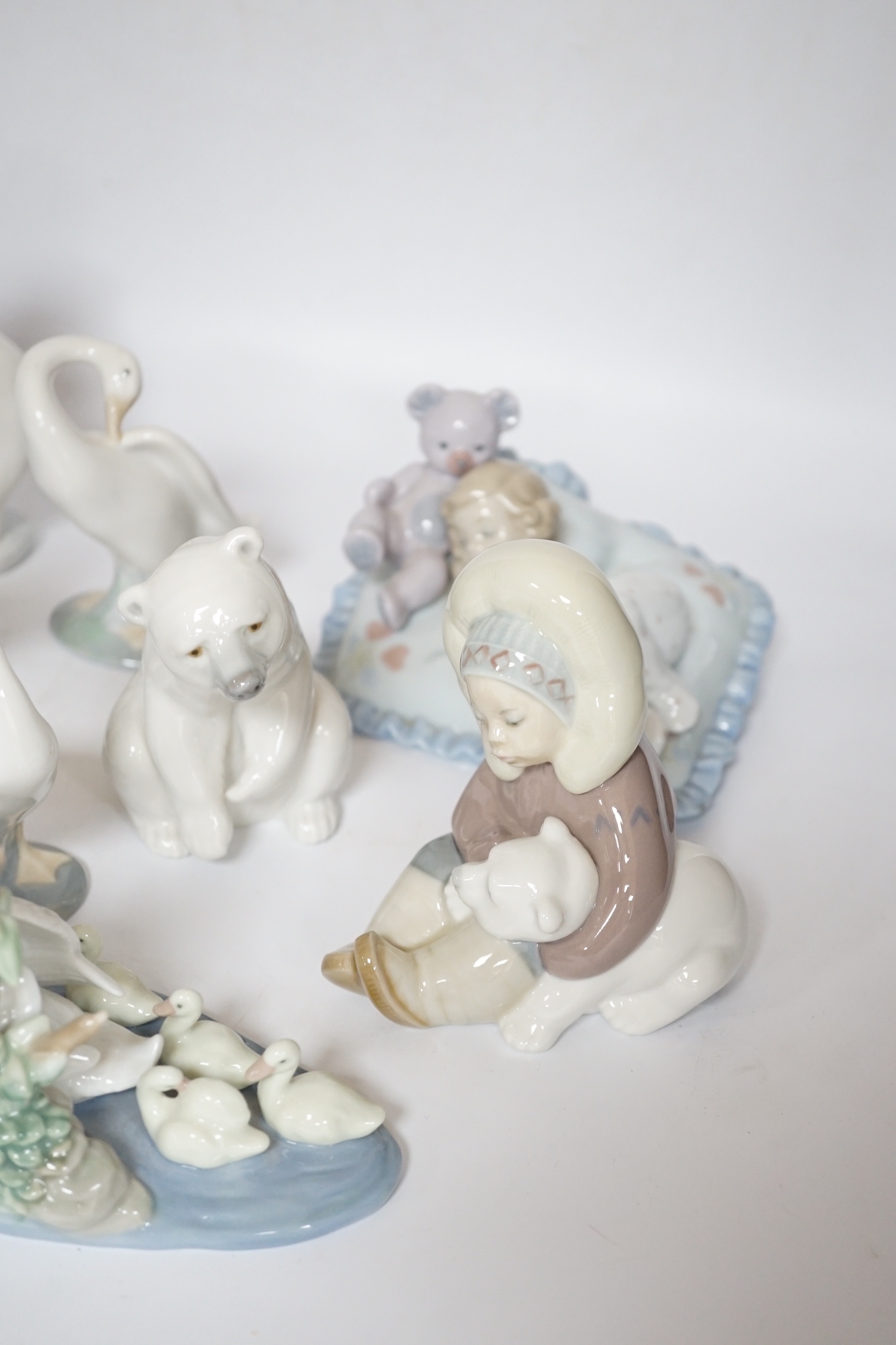 Eleven Lladro figure groups, including a collection of ducks, two Eskimo figure groups, a sleeping child with teddy on a cushion etc, none boxed